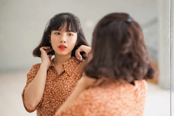 Woman with red lipstick looks at herself in the mirror